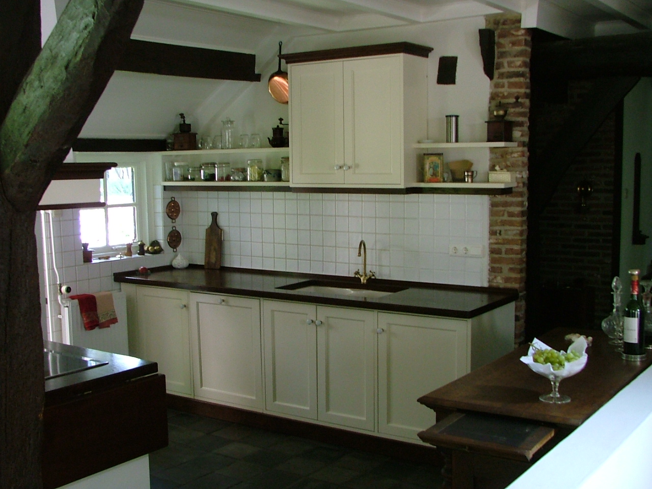 Maatwerk landelijke keuken, uitgevoerd met witte houten kasten en een stenen keukenblad.
