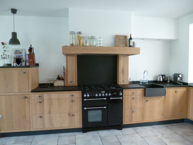 Keuken met landelijk design, met kasten in houtkleur en een zwart keukenblad.